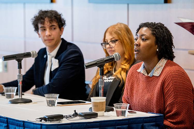 A panel of diverse, young professionals speak at an event